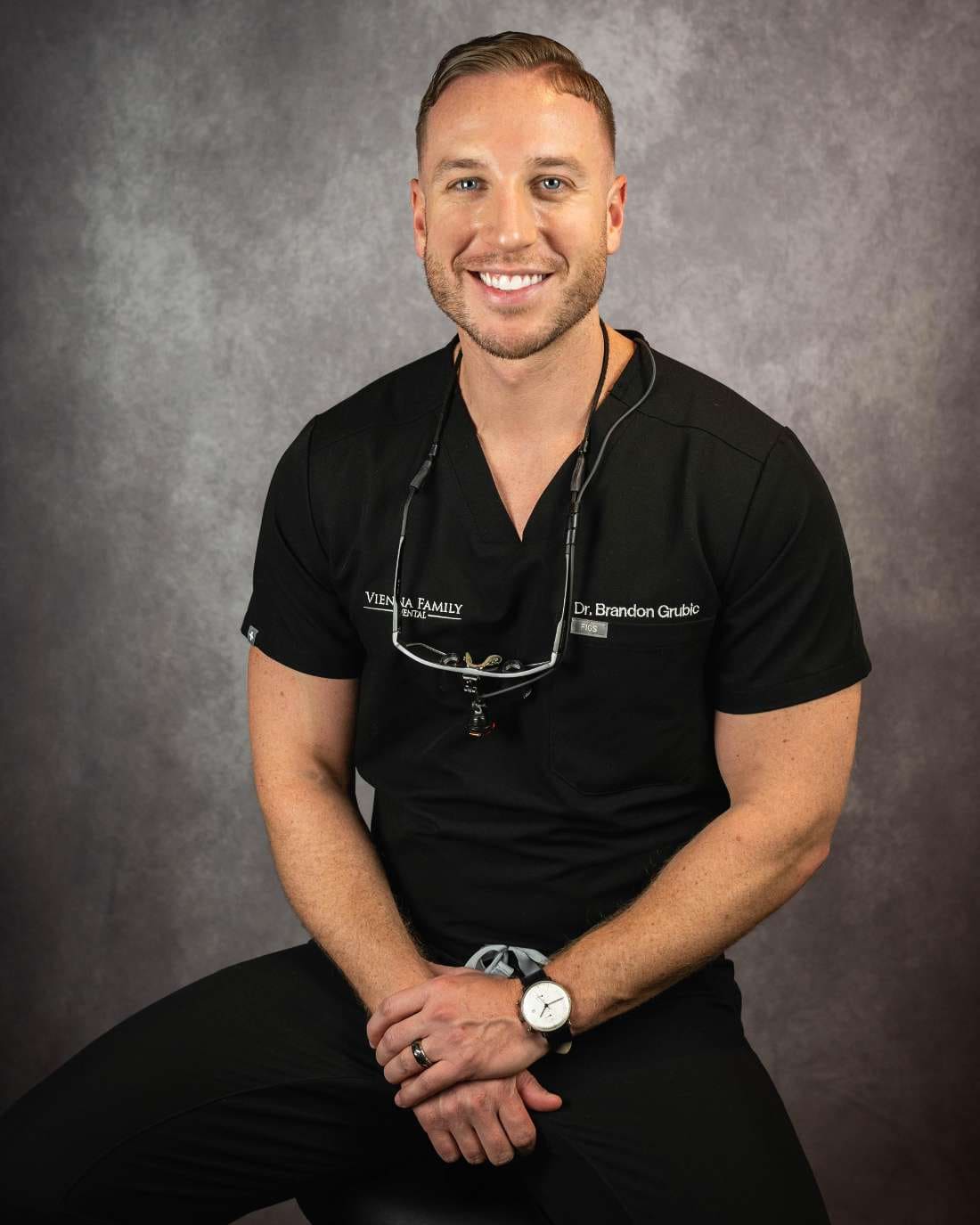 Dr. Brandon Grubic, smiling, in black scrubs