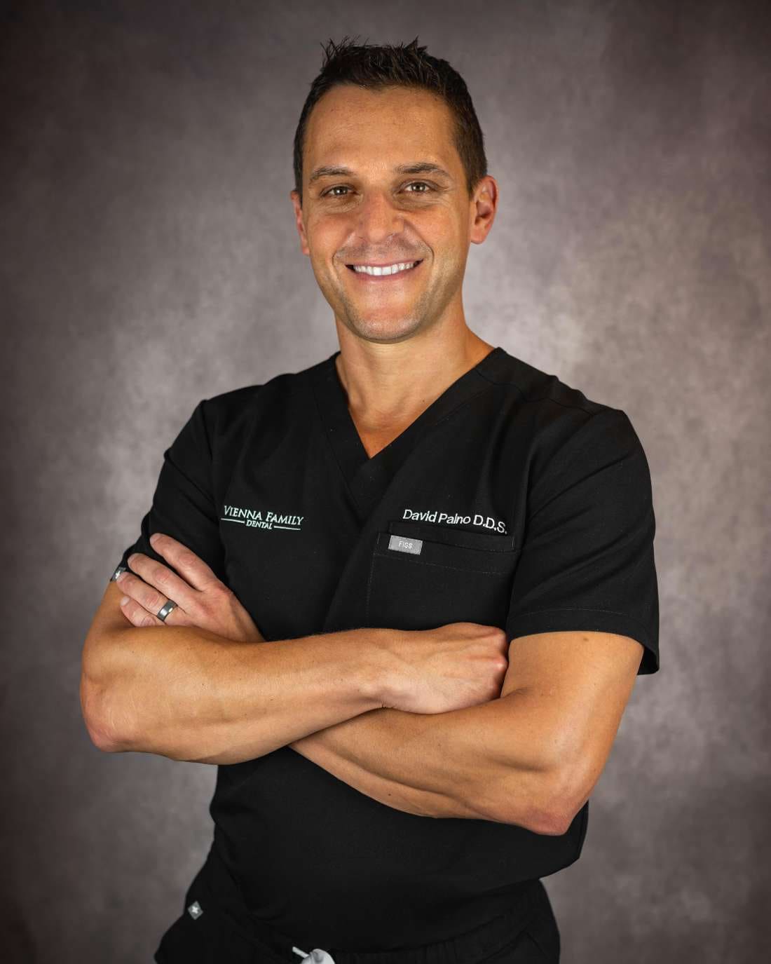 Dr. David Paino in black scrubs, arms crossed, smiling