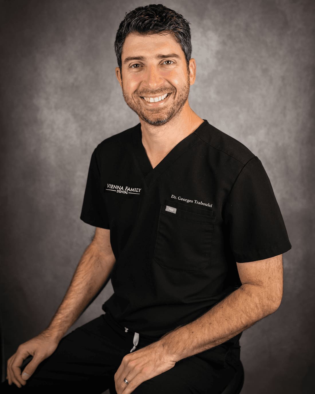 Dr. Georges Traboulsi, smiling, in black scrubs